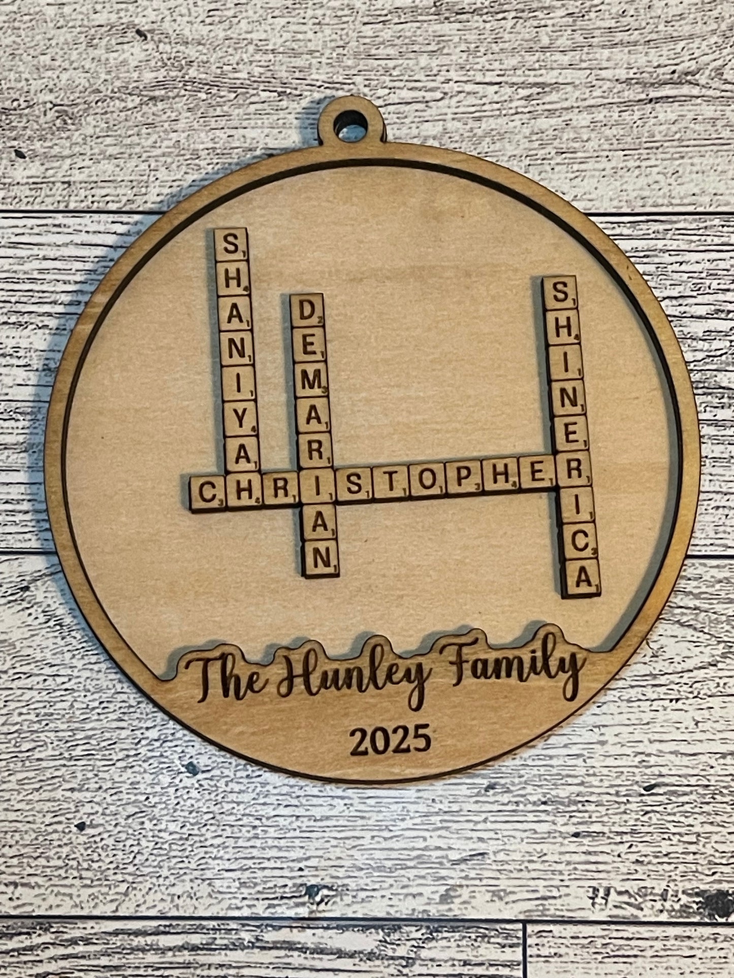 Wooden ornament with crossword-style name design on a wooden surface
