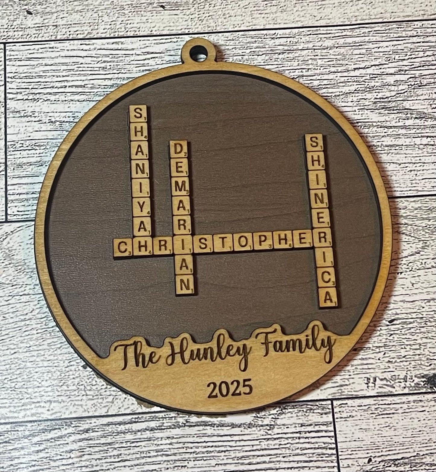 Decorative circular ornament with personalized names and year on a wooden background