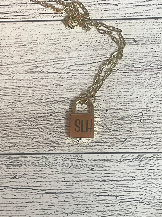 Gold necklace with a padlock pendant on a wooden surface