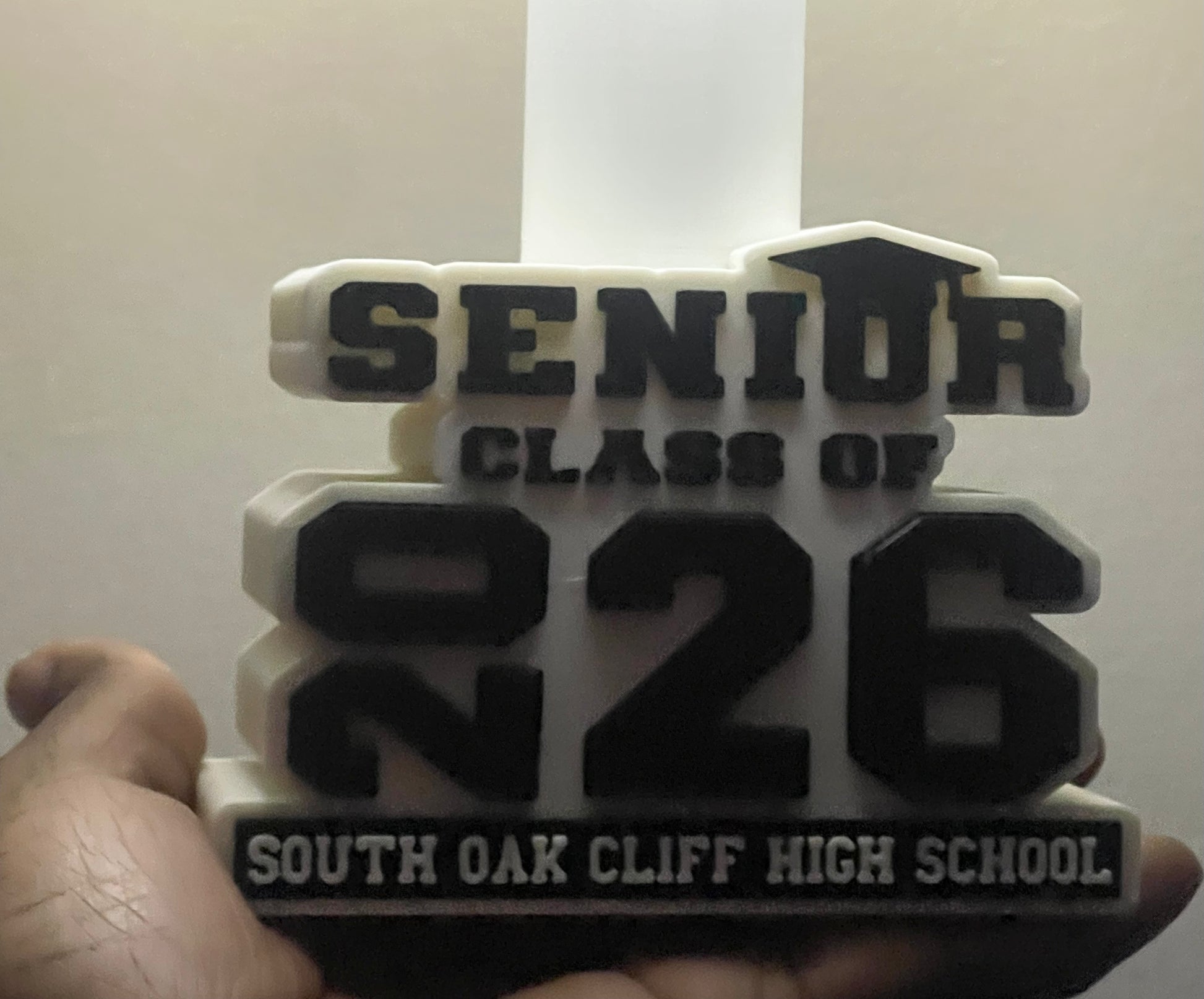 3D-printed plaque with 'Senior Class of 2026' text held by a hand against a white background