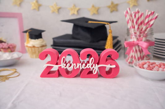 Graduation-themed table setup with '2026 Kennedy' sign, caps, and decorations.