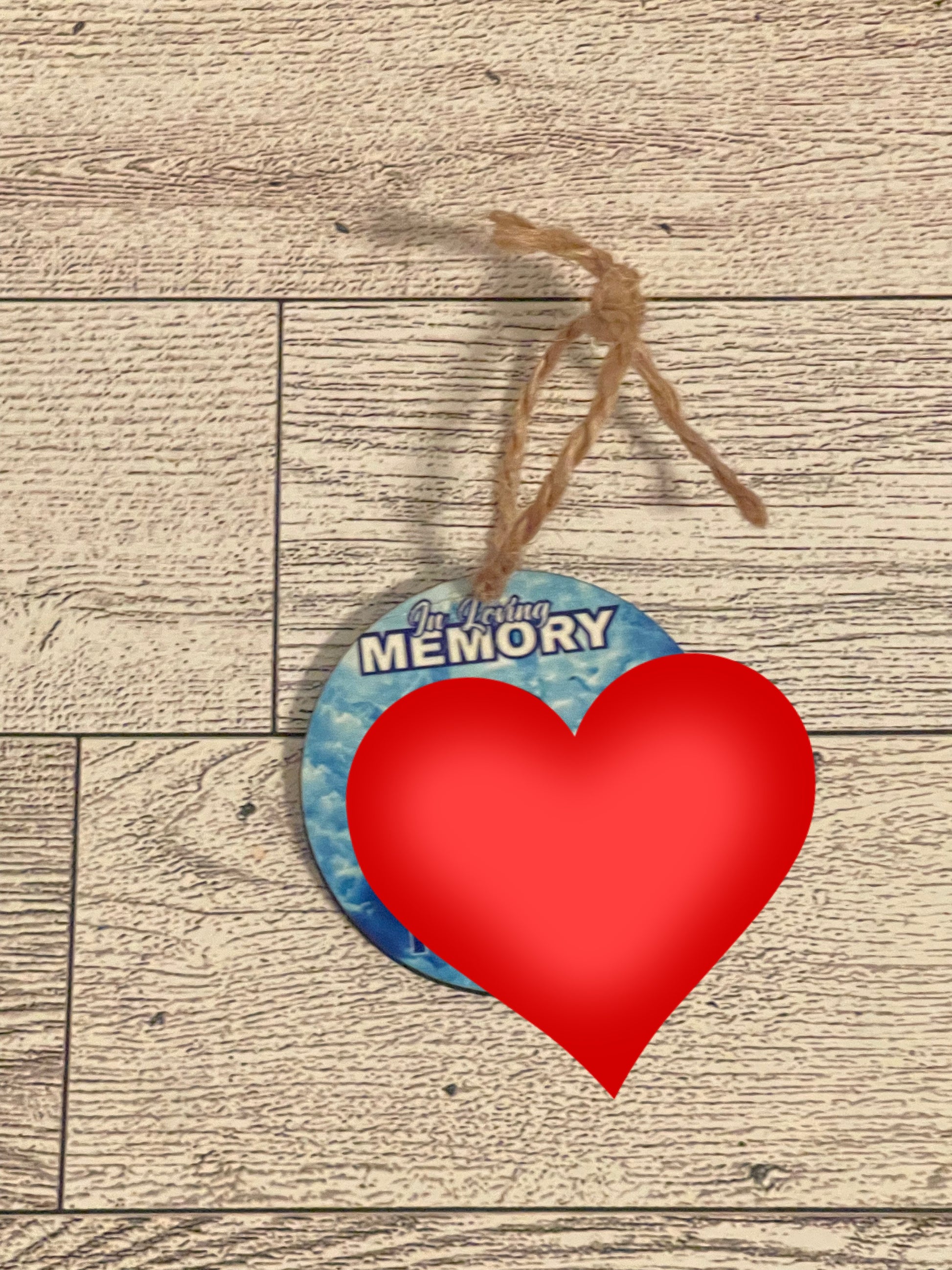 Round ornament with 'In Loving Memory' text and picture on a wooden surface